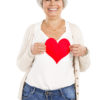 Smiling middle-age woman holding a paper heart silhouette.