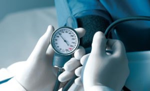 Clinician in white gloves measures blood pressure.