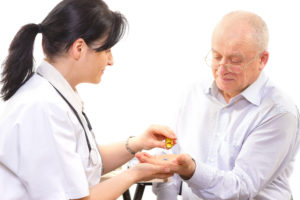 Female physician give medicine tablets to senior male patient.