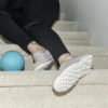 Woman's legs after falling on indoor carpeted stairs with child's ball near her feet.