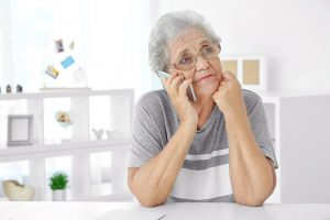 Elderly woman speaking on cell phone at home