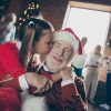 Grandaughter Kisses her Grandpa, who is wearing a Santa cap, at the family holiday party.