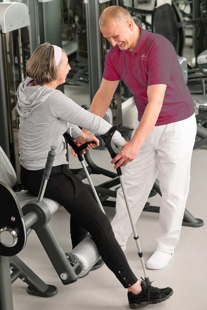 Physical therapist and woman patient using exercise equipment.