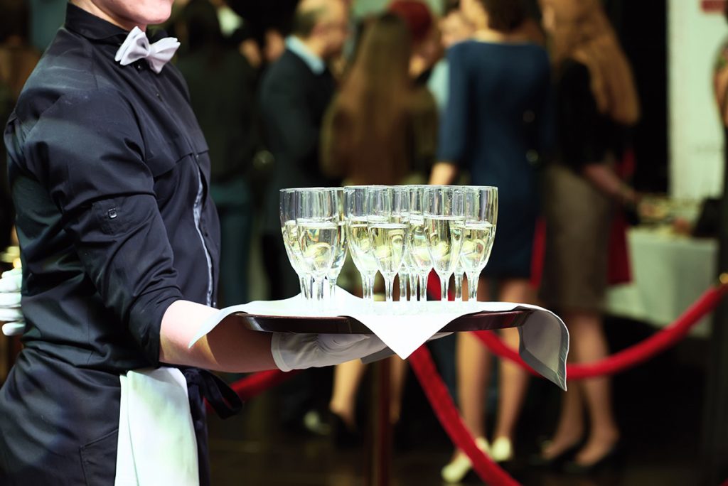Server presenting a tray of champagne glasses.