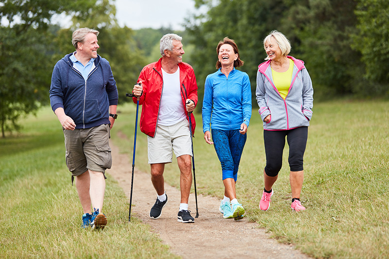 Group of four healthy seniors taking a walk together outdoors. 