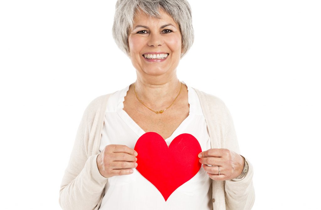 Senior woman smiling and holding a paper valentine.